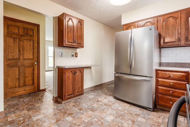 2655 Blendon Woods Blvd Unit 2644, Columbus, OH 43231 - kitchen with freestanding refrigerator, light countertops, decorative backsplash, brown cabinets, and stone finish floors