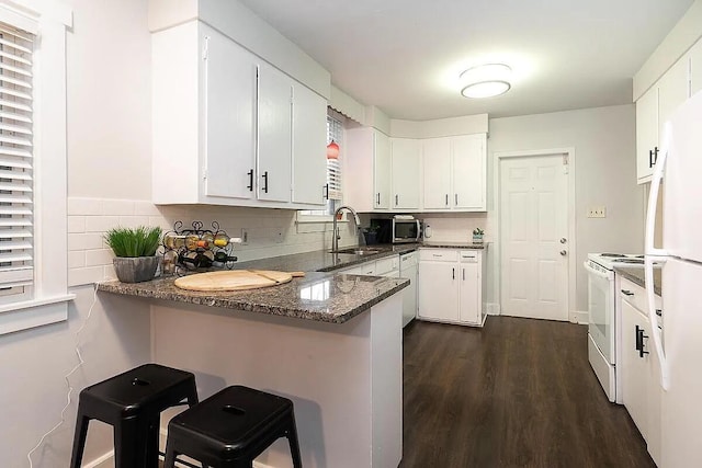 184 E Patterson Ave, Columbus, OH 43202 - kitchen with white appliances, a peninsula, dark wood-type flooring, white cabinetry, and tasteful backsplash