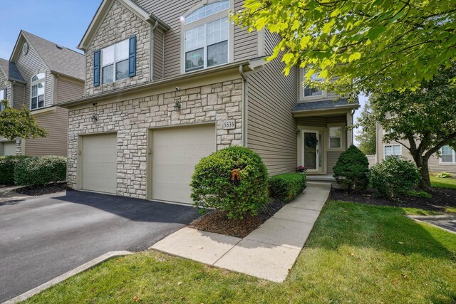 5535 Village Xing, Hilliard, OH 43026 - view of front facade with stone siding, a garage, and asphalt driveway