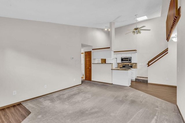 978 Kingsbury Ct, Newark, OH 43055 - unfurnished living room with ceiling fan, high vaulted ceiling, carpet flooring, and stairs
