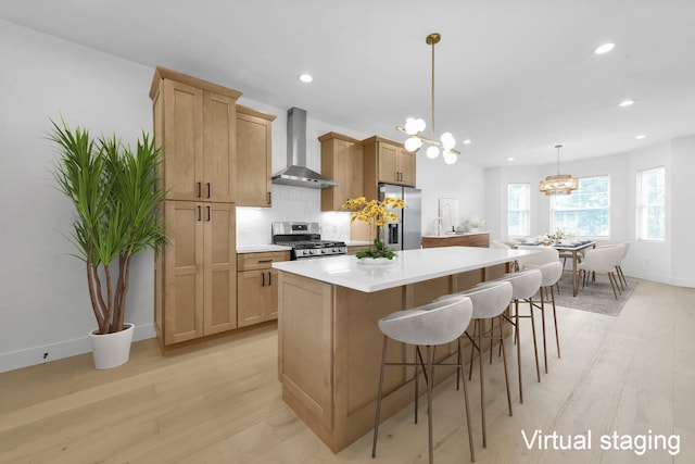 376 E Markison Ave, Columbus, OH 43207 - kitchen with wall chimney range hood, appliances with stainless steel finishes, a chandelier, light wood-style flooring, and backsplash