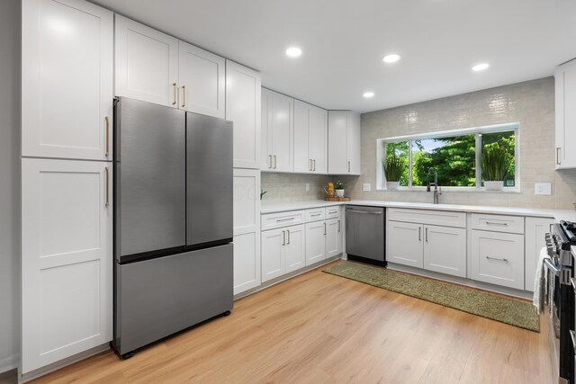 75 S Gould Rd, Columbus, OH 43209 - kitchen with stainless steel appliances, decorative backsplash, light wood-style flooring, white cabinetry, and recessed lighting