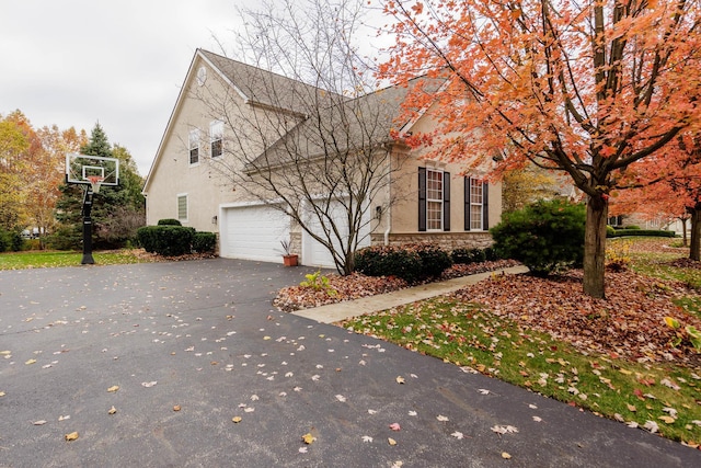 5893 Dunheath Loop, Dublin, OH 43016 - view of front of home featuring driveway, a garage, stucco siding, and stone siding