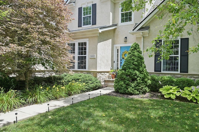 5893 Dunheath Loop, Dublin, OH 43016 - doorway to property featuring stucco siding, stone siding, and a yard