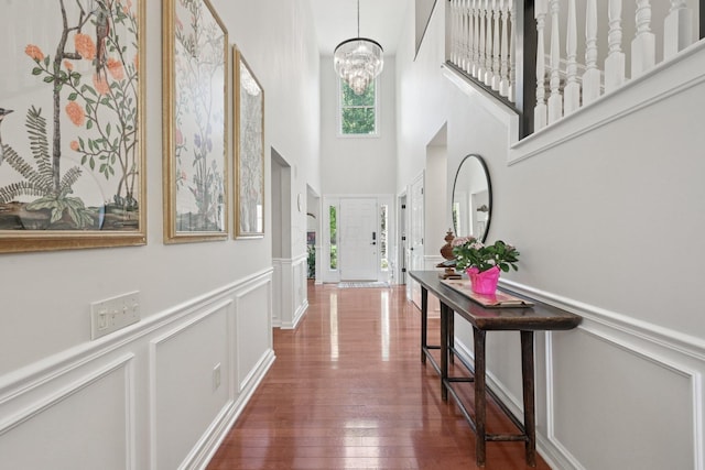 5893 Dunheath Loop, Dublin, OH 43016 - hallway featuring a decorative wall, a high ceiling, wainscoting, a chandelier, and dark wood-style flooring