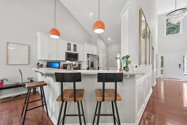 5893 Dunheath Loop, Dublin, OH 43016 - kitchen with high vaulted ceiling, stainless steel appliances, a breakfast bar, dark wood finished floors, and white cabinetry