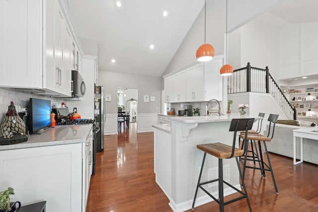 5893 Dunheath Loop, Dublin, OH 43016 - kitchen featuring appliances with stainless steel finishes, dark wood-style flooring, white cabinetry, a breakfast bar area, and a wainscoted wall