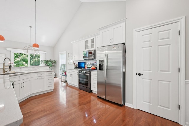 5893 Dunheath Loop, Dublin, OH 43016 - kitchen with appliances with stainless steel finishes, high vaulted ceiling, white cabinetry, glass insert cabinets, and light wood-style floors