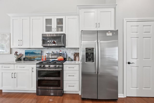 5893 Dunheath Loop, Dublin, OH 43016 - kitchen with stainless steel appliances, white cabinets, dark wood-style flooring, decorative backsplash, and glass insert cabinets