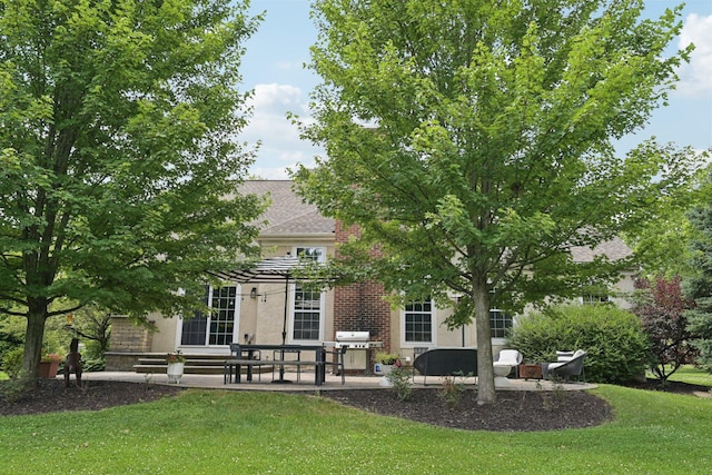 5893 Dunheath Loop, Dublin, OH 43016 - back of house featuring a patio, a lawn, a shingled roof, brick siding, and stucco siding