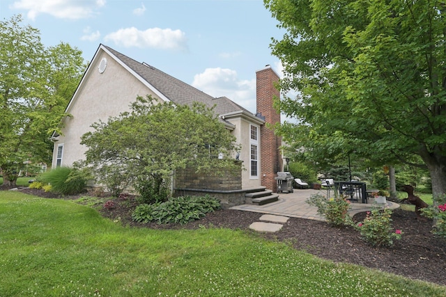 5893 Dunheath Loop, Dublin, OH 43016 - view of property exterior with a chimney, a yard, a patio, and stucco siding