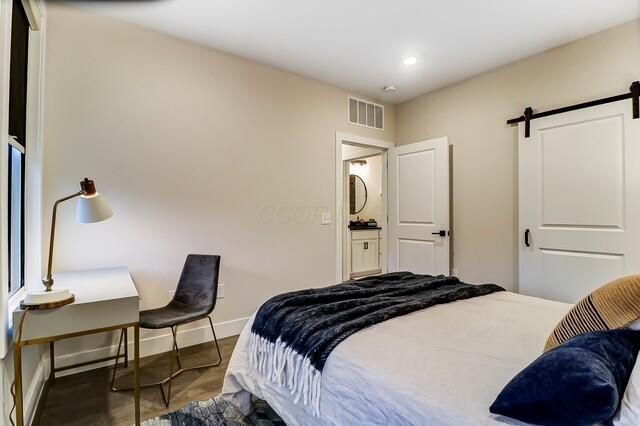 1301 Highland St, Columbus, OH 43201 - bedroom featuring a barn door, baseboards, and recessed lighting