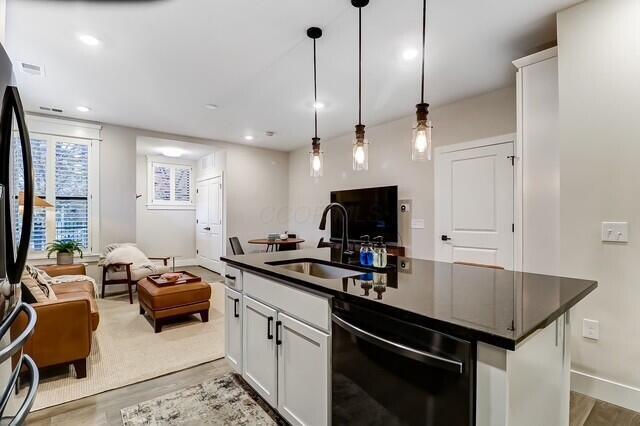 1301 Highland St, Columbus, OH 43201 - kitchen featuring black dishwasher, a sink, dark countertops, open floor plan, and recessed lighting