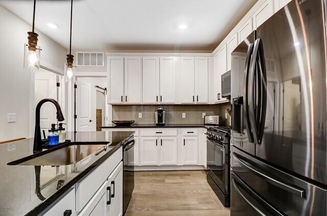 1301 Highland St, Columbus, OH 43201 - kitchen with fridge with ice dispenser, black range with gas cooktop, a sink, stainless steel microwave, and light wood finished floors