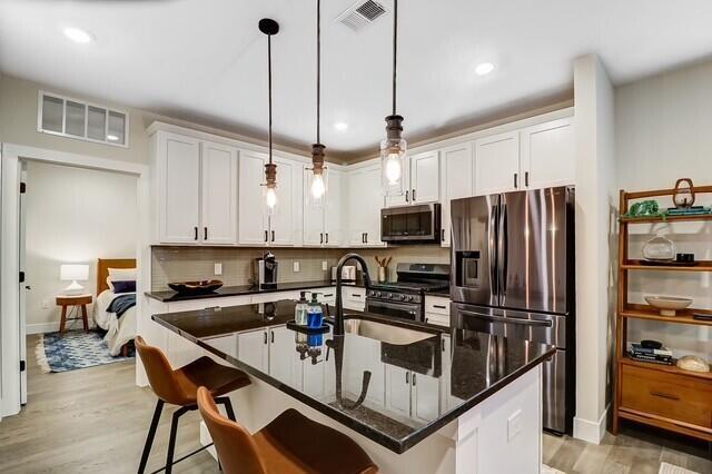 1301 Highland St, Columbus, OH 43201 - kitchen with stainless steel appliances, a kitchen breakfast bar, white cabinets, pendant lighting, and recessed lighting