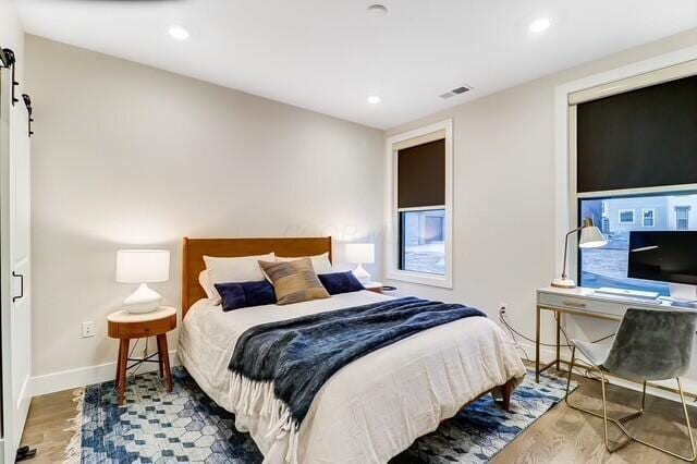 1301 Highland St, Columbus, OH 43201 - bedroom featuring wood finished floors, baseboards, recessed lighting, and a barn door