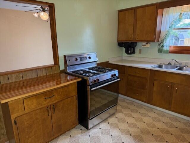 2377 E Howard Rd, Obetz, OH 43207 - kitchen with gas stove, brown cabinets, a ceiling fan, light countertops, and light flooring