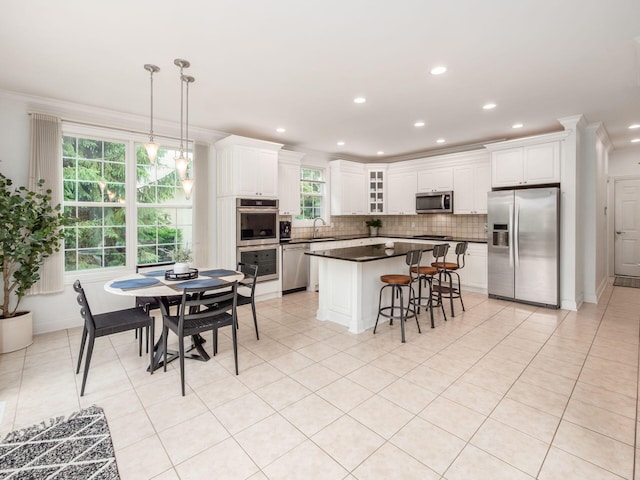 6165 Avocet Ct, Dublin, OH 43017 - kitchen with appliances with stainless steel finishes, backsplash, dark countertops, white cabinetry, and crown molding