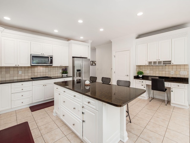 6165 Avocet Ct, Dublin, OH 43017 - kitchen featuring appliances with stainless steel finishes, light tile patterned flooring, decorative backsplash, a breakfast bar, and white cabinetry