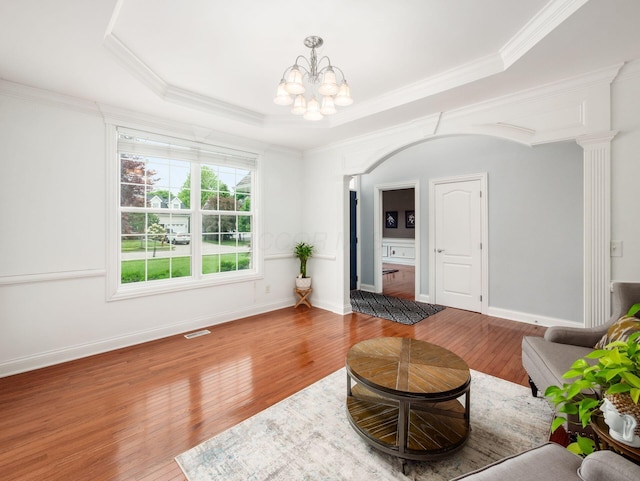 6165 Avocet Ct, Dublin, OH 43017 - living area featuring wood finished floors, a chandelier, ornamental molding, arched walkways, and a tray ceiling