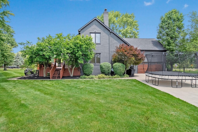 2946 Lewis Center Rd, Lewis Center, OH 43035 - back of house featuring a trampoline, stairway, a lawn, and stucco siding