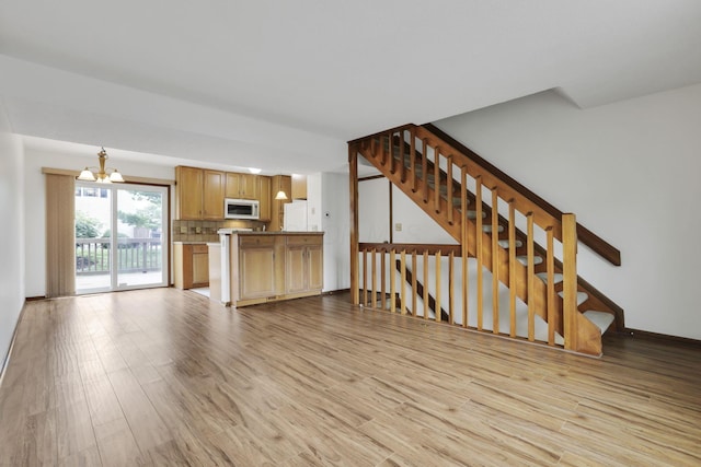 5062 Stoneybrook Blvd Unit 3F, Hilliard, OH 43026 - unfurnished living room featuring light wood-type flooring, a chandelier, and stairs
