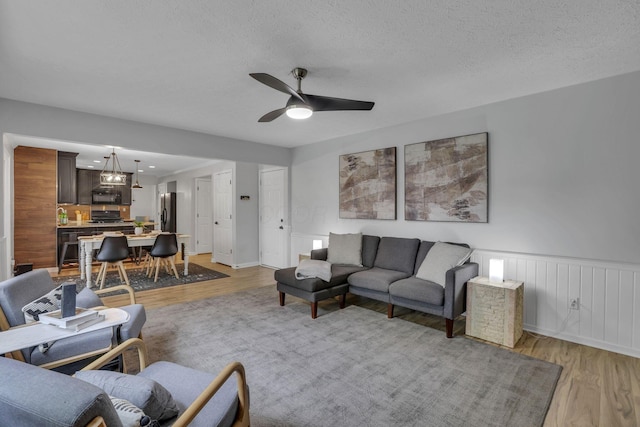 13680 Nantucket Ave NW, Pickerington, OH 43147 - living room featuring a ceiling fan, light wood-type flooring, wainscoting, and a textured ceiling