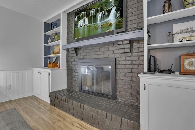 13680 Nantucket Ave NW, Pickerington, OH 43147 - unfurnished living room with wood finished floors, a wainscoted wall, a fireplace, and built in shelves
