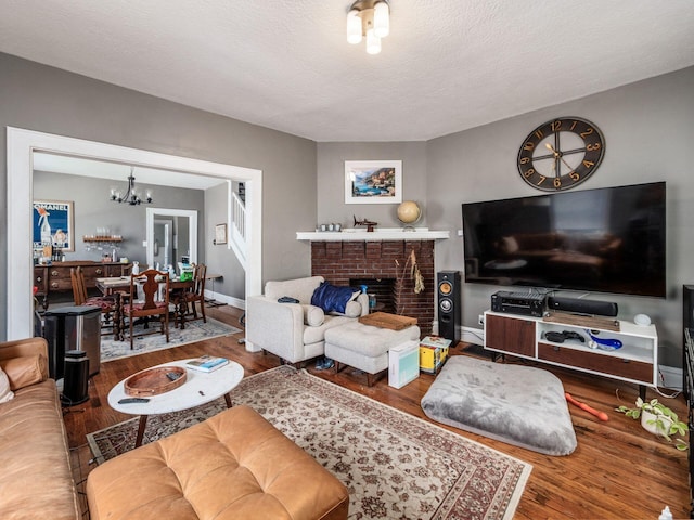1364-1366 S 3rd St, Columbus, OH 43207 - living room with wood finished floors, a chandelier, baseboards, a textured ceiling, and a fireplace