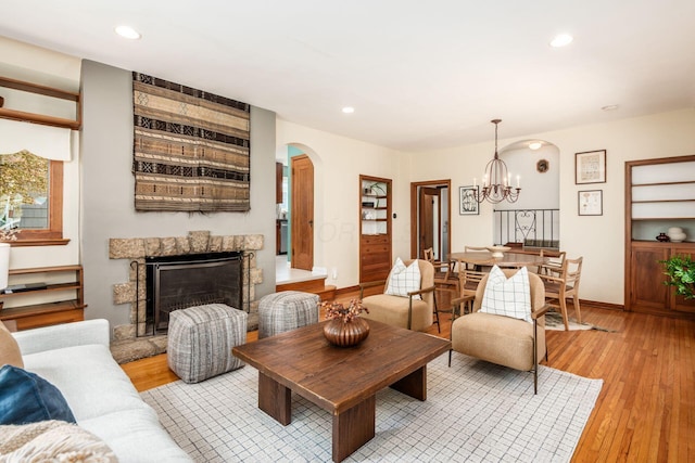 328 Chatham Rd, Columbus, OH 43214 - living room with arched walkways, light wood-type flooring, a chandelier, recessed lighting, and a fireplace with raised hearth