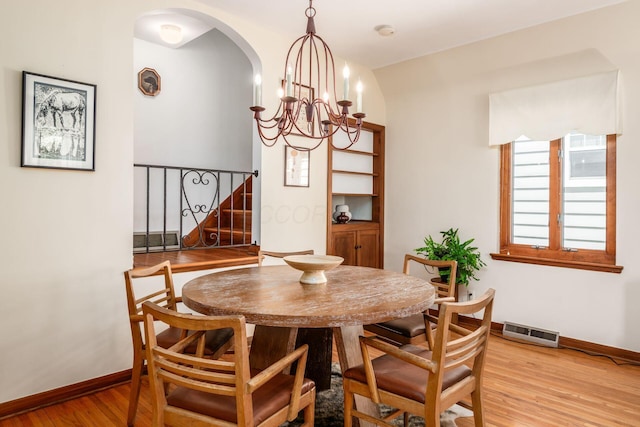 328 Chatham Rd, Columbus, OH 43214 - dining area with light wood-style flooring, arched walkways, a chandelier, and stairway
