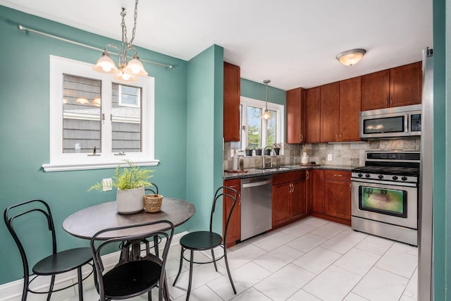 328 Chatham Rd, Columbus, OH 43214 - kitchen featuring appliances with stainless steel finishes, a chandelier, decorative backsplash, and hanging light fixtures