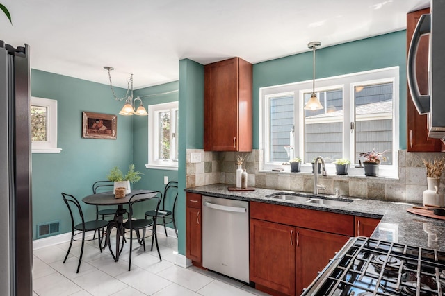 328 Chatham Rd, Columbus, OH 43214 - kitchen featuring appliances with stainless steel finishes, decorative backsplash, dark stone counters, and decorative light fixtures