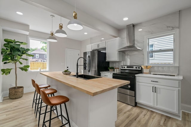 591 S 22nd St, Columbus, OH 43205 - kitchen with wall chimney exhaust hood, appliances with stainless steel finishes, butcher block countertops, a breakfast bar area, and an island with sink