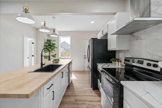 591 S 22nd St, Columbus, OH 43205 - kitchen with stainless steel appliances, wall chimney exhaust hood, butcher block counters, light wood finished floors, and white cabinets