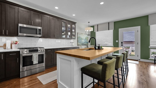1098 Oregon Ave, Columbus, OH 43201 - kitchen with stainless steel appliances, butcher block counters, backsplash, dark brown cabinets, and dark wood finished floors