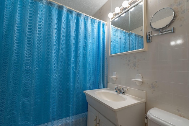591 Knights Ave, Columbus, OH 43230 - full bathroom with tile walls, vanity, and a textured ceiling
