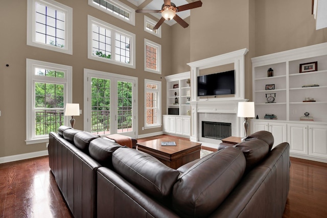125 Fallen Ash Dr, Granville, OH 43023 - living room with a ceiling fan, dark wood finished floors, a towering ceiling, a fireplace, and built in shelves