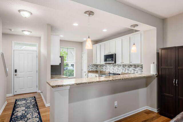 4609 Stoneworth Dr Unit 58, Hilliard, OH 43026 - kitchen featuring stainless steel microwave, white cabinetry, tasteful backsplash, light stone countertops, and light wood-style floors