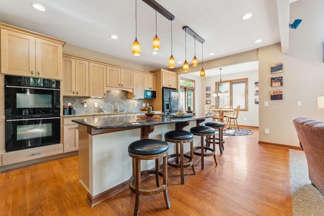 332 Waters Edge Dr, Hebron, OH 43025 - kitchen featuring black appliances, light brown cabinetry, a breakfast bar, light wood finished floors, and recessed lighting