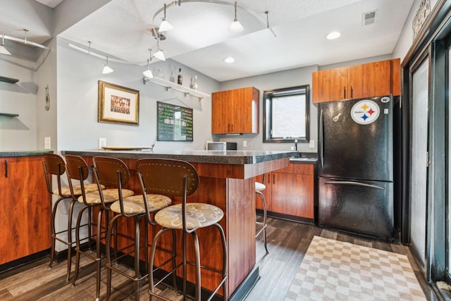 332 Waters Edge Dr, Hebron, OH 43025 - kitchen featuring freestanding refrigerator, brown cabinets, a kitchen breakfast bar, track lighting, and recessed lighting