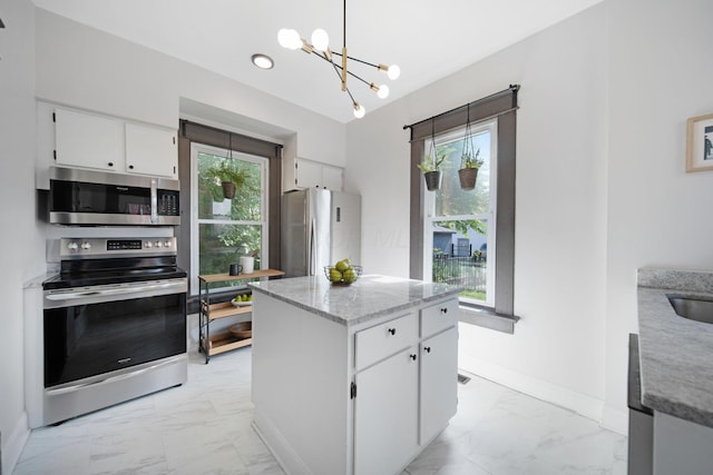 1214 Hamlet St, Columbus, OH 43201 - kitchen with stainless steel appliances, light marble finish flooring, a chandelier, white cabinets, and light stone counters
