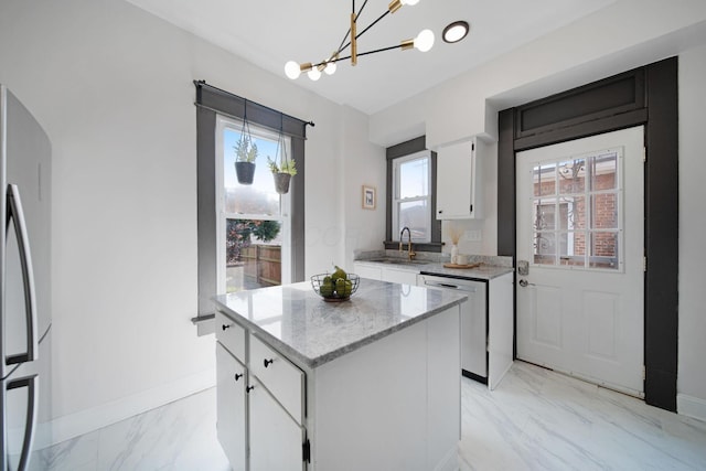 1214 Hamlet St, Columbus, OH 43201 - kitchen featuring stainless steel dishwasher, freestanding refrigerator, light marble finish floors, a chandelier, and white cabinets