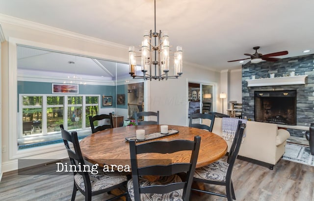 525 Floral Valley Dr W, Howard, OH 43028 - dining space with crown molding, wood finished floors, a chandelier, a ceiling fan, and a fireplace