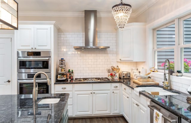 525 Floral Valley Dr W, Howard, OH 43028 - kitchen featuring wall chimney exhaust hood, appliances with stainless steel finishes, a chandelier, decorative backsplash, and white cabinetry