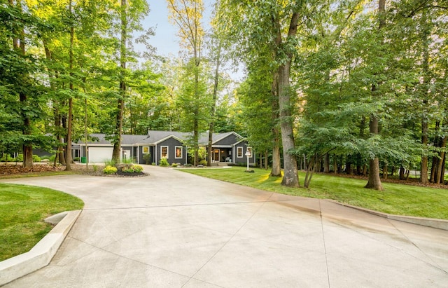 525 Floral Valley Dr W, Howard, OH 43028 - view of front of home with curved driveway, a front lawn, view of wooded area, and a garage
