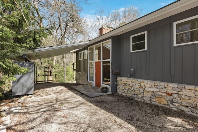 220 Hardy Way, Worthington, OH 43085 - view of exterior entry with stone siding, a chimney, and board and batten siding