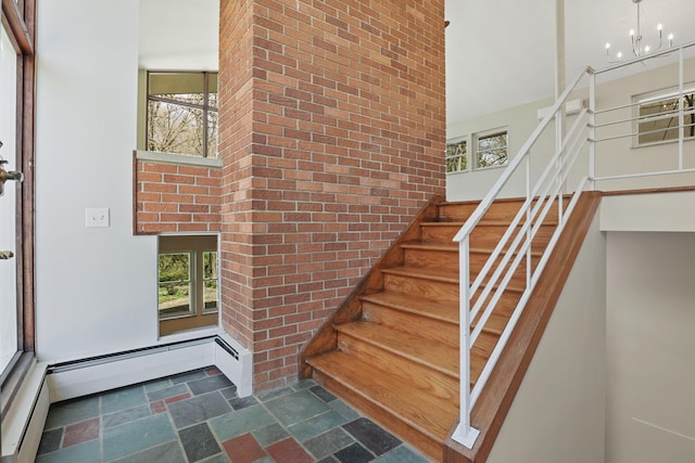 220 Hardy Way, Worthington, OH 43085 - staircase with stone tile floors, plenty of natural light, brick wall, a chandelier, and baseboard heating