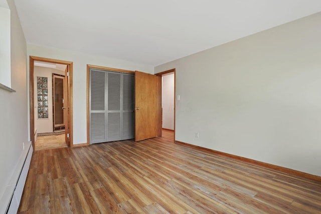 220 Hardy Way, Worthington, OH 43085 - unfurnished bedroom with a baseboard heating unit, wood finished floors, a closet, and baseboards