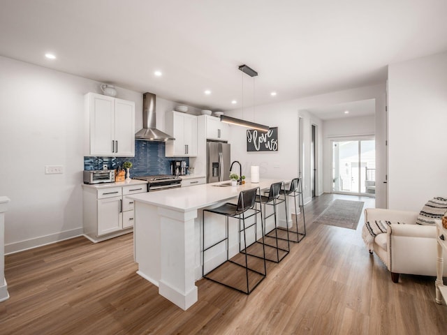 1210 Madison Ave, Columbus, OH 43205 - kitchen featuring wall chimney exhaust hood, stainless steel fridge, gas range oven, light wood-type flooring, and white cabinetry